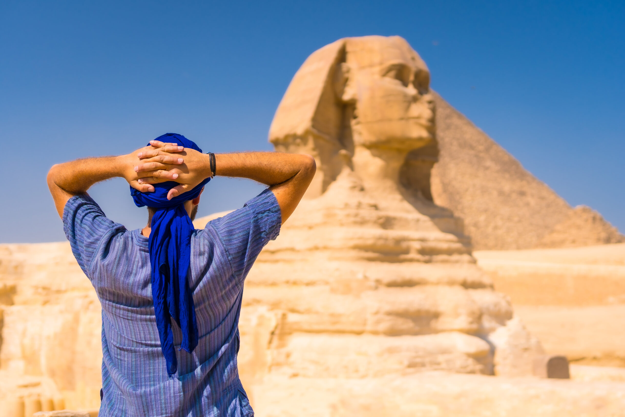 Um jovem turista usando um turbante azul perto da Grande Esfinge de Gizé, Cairo, Egito